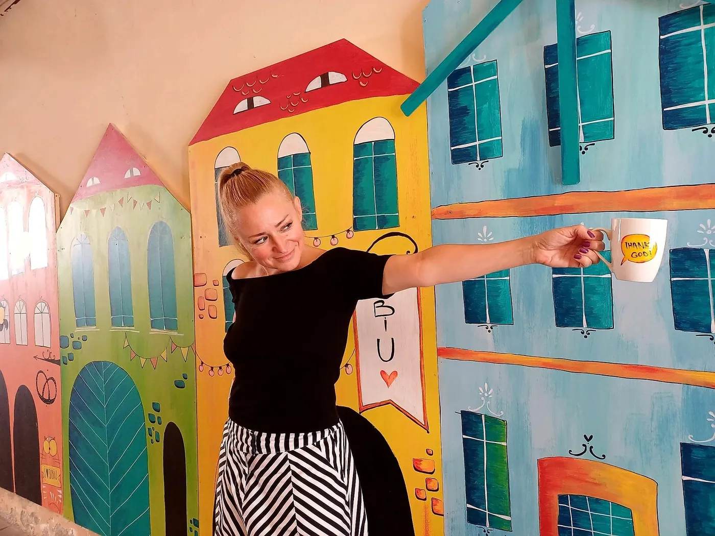 Alexandra junto a las casitas pintadas de Sibiu de Lullula, con una taza en la mano