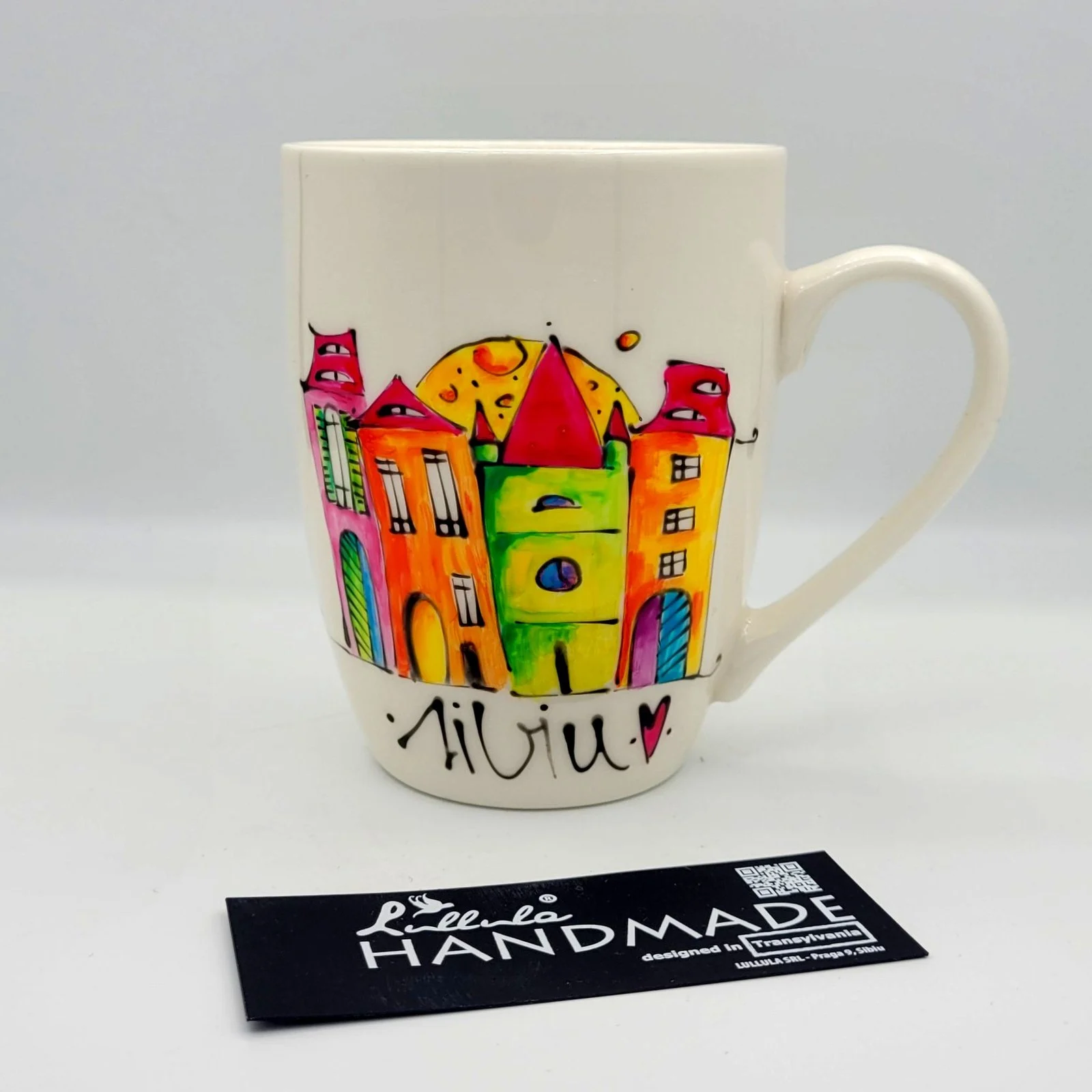 Cană Sibiu pictată manual, cu case colorate cu ochi pe acoperiș